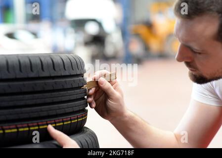 Mechaniker steuert die Profiltiefe der Reifen Stockfoto