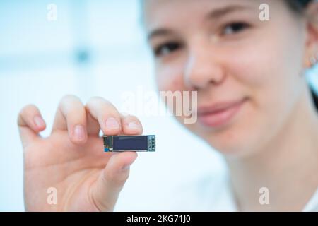 LCD-Miniaturanzeige mit Flüssigkristallanzeige und Hintergrundbeleuchtung mit organischer Leuchtdiode (LED) in den Händen einer jungen Frau Stockfoto