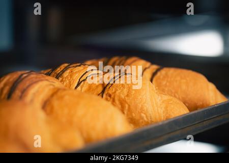 Frisch gebackene Croissants aus der Nähe in einer Bäckerei auf unscharfem Hintergrund. Stockfoto