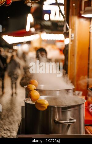 Glühwein in großen Töpfen mit Orangen, der auf dem Weihnachtsmarkt in Straßburg verkauft wird Stockfoto