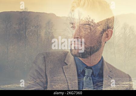 Der Mann mit vielen Gedanken. Zusammengesetztes Bild eines hübschen Mannes, überlagert mit einem Bild eines Waldes. Stockfoto