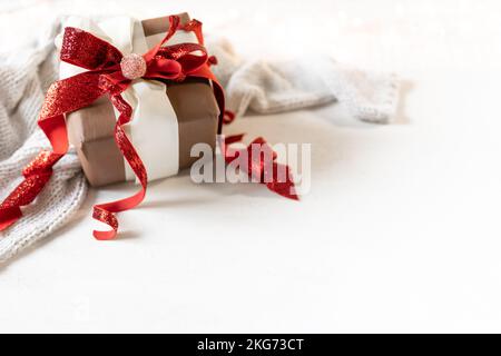 Festlicher Hintergrund mit Geschenkbox und Strickelement auf weißem Hintergrund. Stockfoto
