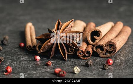 Aromatische Zimtschnecken und Anise auf schwarzem Tisch, Nahaufnahme. Stockfoto