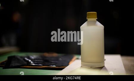 Kleber auf dem Tisch. Behälter mit Klebstoff. Objekt auf dem Tisch. Weißer Kanister. Details zur Zimmereiwerkstatt. Stockfoto