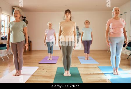 Fitness, Yoga und ältere Frauen in einem Kurs, um sich zu entspannen und ein ruhiges, Workout und friedliche Meditation in einem Studio zu starten. Wellness, Freunde oder Zen Senior Stockfoto