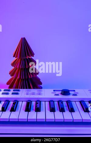 Weihnachtlicher Hintergrund mit Midi-Tastatur und Weihnachtsdekor mit Neonlicht. Stockfoto