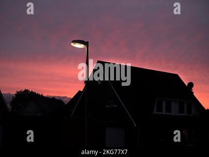 Silhouette von Häusern vor einem atemberaubenden roten Sonnenuntergang, der die ruhige Schönheit eines Sommerabends in der Stadt einfängt. Stockfoto