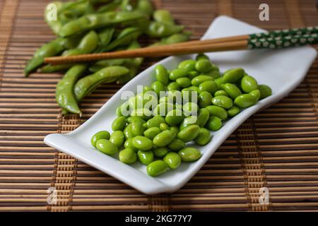 Edamam-Sojabohnen auf weißem Tablett mit Stäbchen Stockfoto