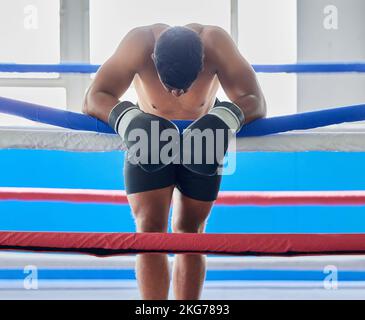 Fitness, müde und traurig Boxer nach einem Verlust Denken über seine Niederlage in einem schwierigen Kampf in einem Boxring in einem Fitnessstudio. Müdigkeit, Verlierer und Stockfoto