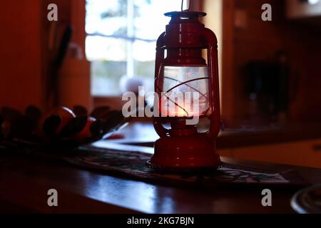 Weihnachtsdämmerung, rote Retro-Lampe, die als Weihnachtsdekoration auf der aufgestickten Serviette steht Stockfoto