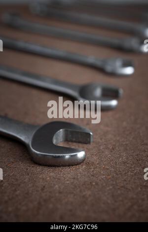 Nahaufnahme von Schraubenschlüsseln oder Maulschlüsseln auf einer Holzplatte in der Werkstatt mit selektivem Fokus auf dem Schraubenschlüsselkopf Stockfoto