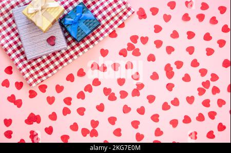 Geschenkschachteln und rosa Hintergrund mit kleinen Herzen, flach liegend. Stockfoto