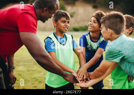 Sporttrainer, der mit seinem Team auf einem Schulfeld zusammenkommt. Rugby-Trainer gibt seinen Schülern vor dem Training ein Motivationsgespräch. Sport-Mentorin Stockfoto