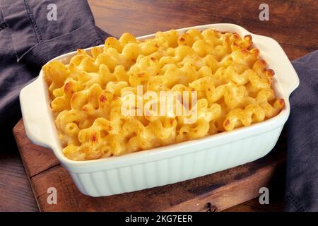 Makkaroni und Käsepasta in einem Auflauf auf einem rustikalen Holztisch. Traditionelle amerikanische Küche Stockfoto
