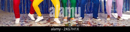 Beine von fünf unbekannten Männern und Frauen, die auf farbigen Konfetti auf der Disco-Party tanzen. Stockfoto