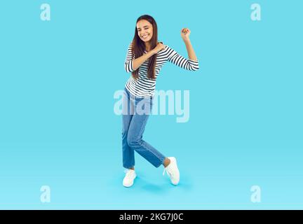 Großes Foto einer jungen Brünette in einem gestreiften Sweatshirt und blauen Jeans, die herumalbern und tanzen Stockfoto