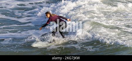 Surfer an einem schönen Tag am Bournemouth Pier, 20.. November 2022kneeling Stockfoto