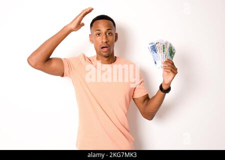 Ein junger Mann mit Geld, isoliert vor weißem Hintergrund. Stockfoto