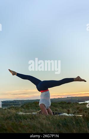Knifflige Yoga-Pose bei Sonnenaufgang im Freien Stockfoto