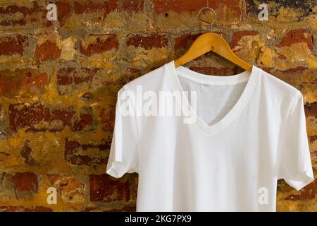 T-Shirt hängt am Kleiderbügel und Kopierbereich auf Ziegelhintergrund Stockfoto