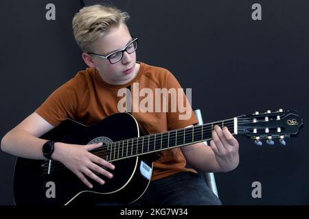 Schüler einer Sekundarschule spielt während des Musikunterrichts Gitarre. holland. Vvbvanbree Photografie. Stockfoto