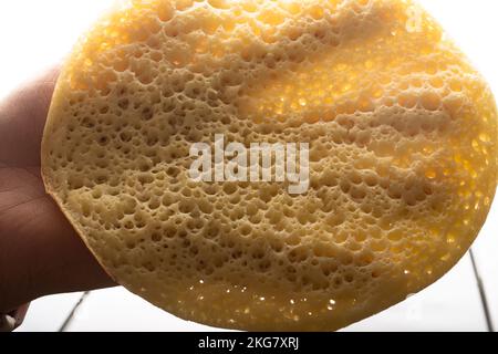 Eine Hand nimmt einen marokkanischen Pfannkuchen, Baghrir typisch marokkanisches Frühstücks-Dessert Stockfoto