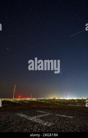 Echtes Sternenfoto von Neowise Comet C2020 F3 NEOWISE bei Mondaufgang. Neumond Halbmond am Horizont über dem Hubschrauberlandeplatz oder Heliport. Henychensk, Ukraine an Stockfoto