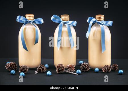 Hausgemachter Eierstockholz in Flaschen mit Pinienzapfen und blauen Kugeln auf dunklem Hintergrund Stockfoto