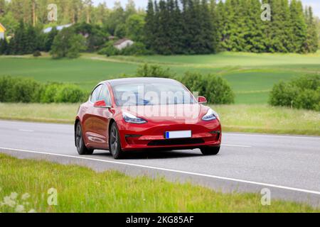 Rotes Tesla Modell 3 Limousine Elektroauto Jahr 2020 mit hoher Geschwindigkeit auf der Autobahn. Salo, Finnland. 23. Juni 2022. Stockfoto