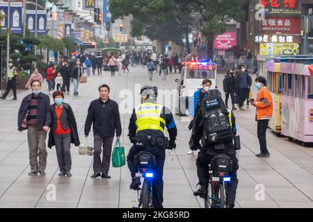 SHANGHAI, CHINA - 22. NOVEMBER 2022 - zwei voll ausgestattete Polizeibeamte fahren Fahrräder, um die Fußgängerzone Nanjing Road in Shanghai, China, zu patrouillieren Stockfoto