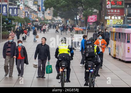 SHANGHAI, CHINA - 22. NOVEMBER 2022 - zwei voll ausgestattete Polizeibeamte fahren Fahrräder, um die Fußgängerzone Nanjing Road in Shanghai, China, zu patrouillieren Stockfoto