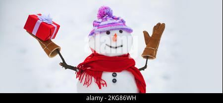 Schneemann mit Schal und Strickmütze. Süße Schneemänner stehen im Winterhintergrund. Grüßt den Schneemann. Stockfoto