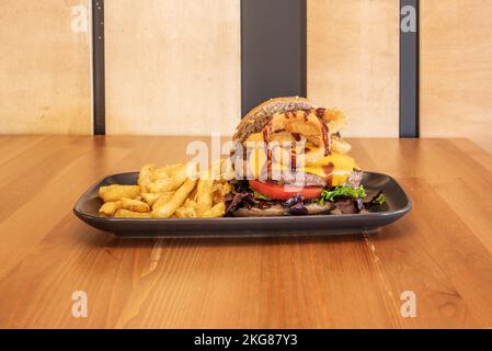 Burger mit vielen Schichten mit Saucen und hausgemachten Pommes frites Stockfoto