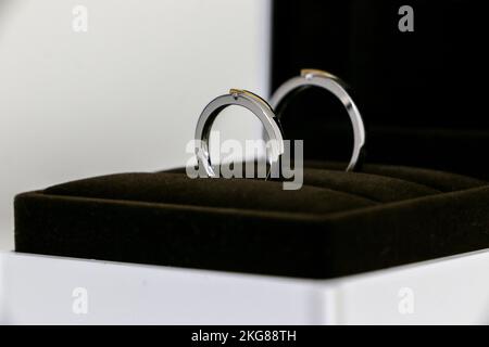 Nahaufnahme eines Paares von Eheringen, die in einer offenen Ringbox funkeln, Symbol für Romantik, Liebe, Ehe. Stockfoto