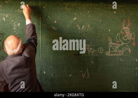 Lehrer an der Schule schreibt auf die Tafel, lustiges Bild Stockfoto