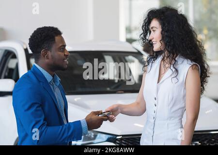 Ein afroamerikanischer Händler gibt dem Kunden den Autoschlüssel Stockfoto