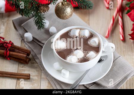 Tasse heiße Schokolade und Marschwalben auf einem Holztisch mit Weihnachtsdekorationen im Hintergrund Stockfoto