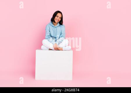 Foto einer fröhlichen, süßen Dame tragen ein stilvolles Sweatshirt sitzen Würfel leer warten Schwarzer freitag Verkauf isoliert auf pinkfarbenem Hintergrund Stockfoto