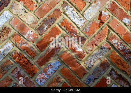 Rote Backsteinwand mit Fischgrätmuster. Diese Ziegelwand hat ein Interessantes Muster, verschiedene Farben und eine raue Textur. Backsteinmauer in Beckenham, Großbritannien Stockfoto