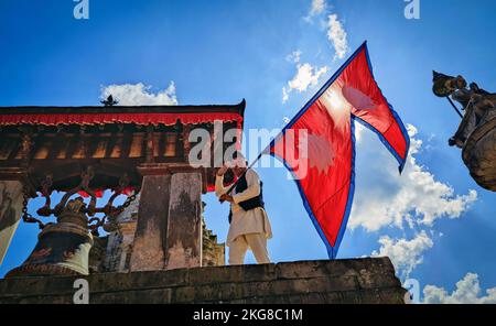 Bhaktapur, Bagmati, Nepal. 22.. November 2022. Am 22. November 2022 schwenkt ein Mann auf dem Durbar-Platz, einem UNESCO-Weltkulturerbe in Bhaktapur, Nepal, die Nationalflagge des Landes. (Bild: © Sunil Sharma/ZUMA Press Wire) Stockfoto