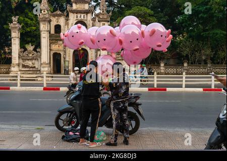 Verkauf rosa Schweineballons auf der Straße vor dem Quan Thanh Tempel während der Rush Hour, Hanoi, Vietnam Stockfoto