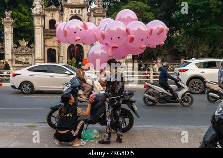 Verkauf rosa Schweineballons auf der Straße vor dem Quan Thanh Tempel während der Rush Hour, Hanoi, Vietnam Stockfoto