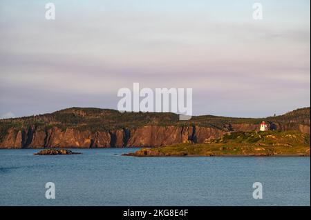 Kanada, Labrador, Neufundland, Trinity, Meeresküste mit entferntem Leuchtturm Fort Point bei Sonnenuntergang