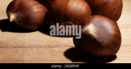 Kastanien, die auf einem hellen Tisch aus Holz stehen Stockfoto