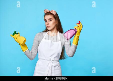 Frau mit Gummihandschuhen wählt zwischen zwei Reinigungsprodukten Stockfoto