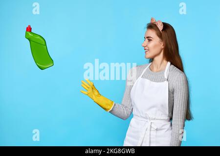 Eine Frau in Gummihandschuhen fängt eine fliegende Flasche Waschmittel Stockfoto