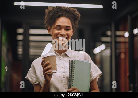 Hochmotivierte Mitarbeiterin, die während ihrer Kaffeepause für die Kamera posiert Stockfoto