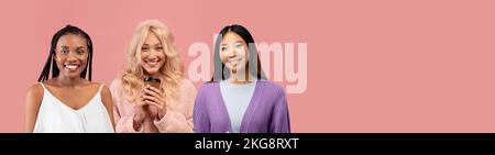 Süße multikulturelle junge Damen, die auf pinkfarbenem Hintergrund posieren Stockfoto