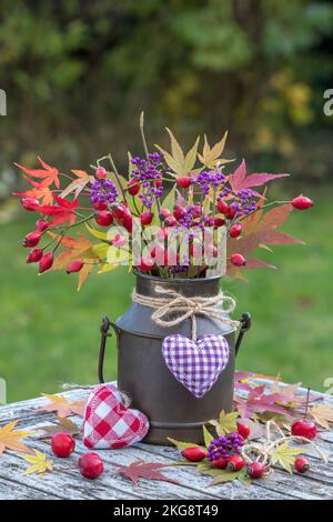 Strauß von Rosenhüften, Bodinier-Beautybeeren und Ahornblättern in klassischer Milch Stockfoto