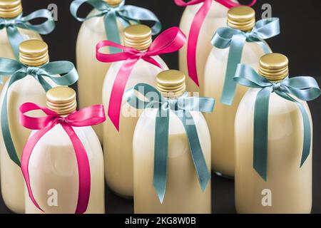 Hausgemachter Eierstockschießen in Flaschen mit blauen und rosa Schleifen auf dunklem Hintergrund Stockfoto